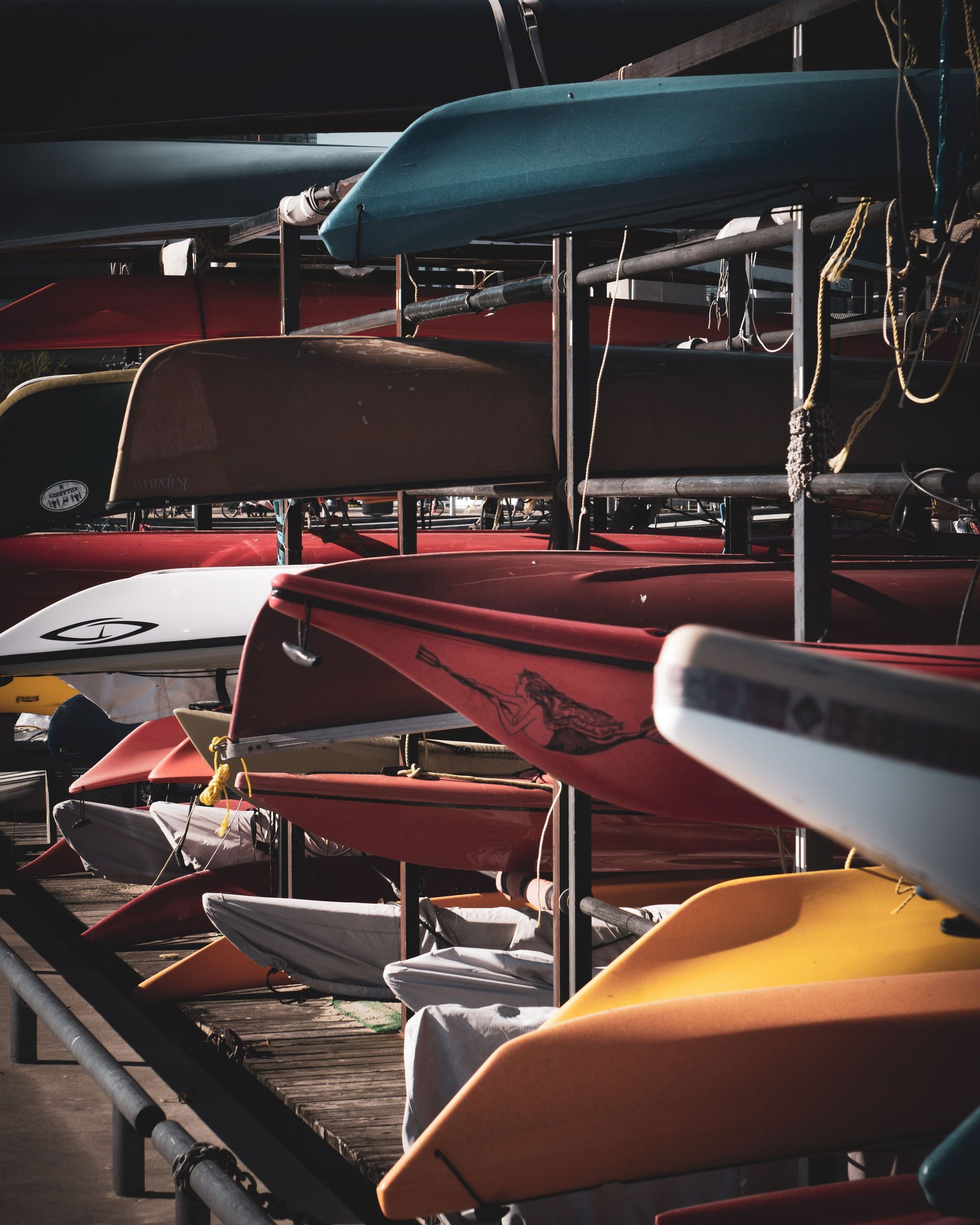 Rows of assorted colorful boats on platforms with ropes in harbor in town