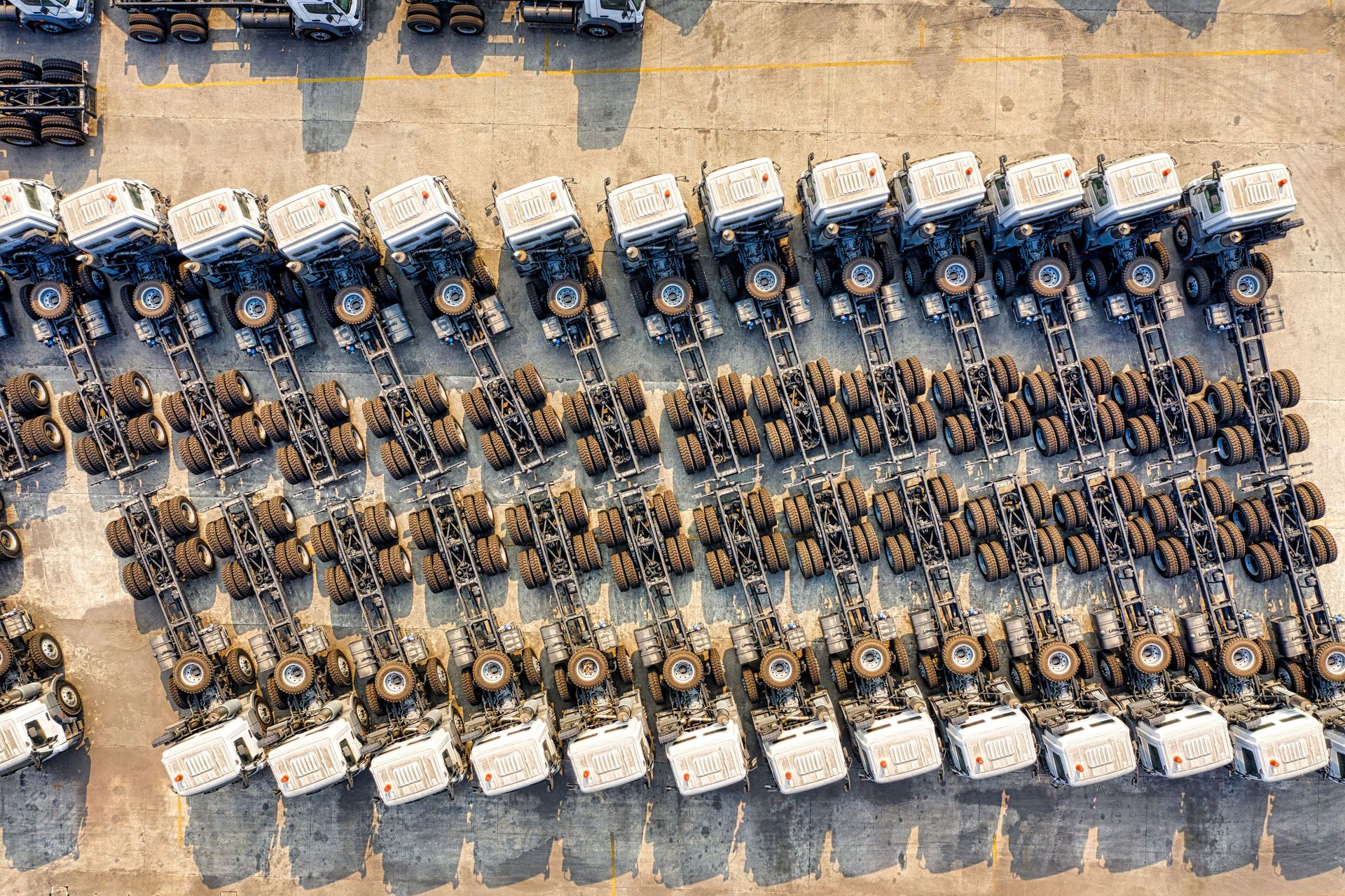 Aerial shot of multiple trucks parked in rows, highlighting transportation logistics.